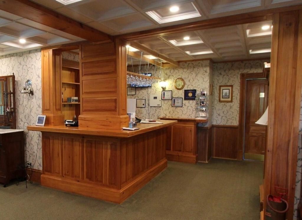 Hotelreceptiebalie met houten lambrisering, behang met patroon en een lobby met vloerbedekking.
