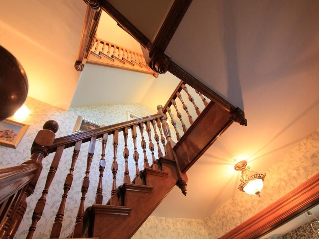 Houten trap met gebeeldhouwde leuning in een sfeervol verlicht interieur.