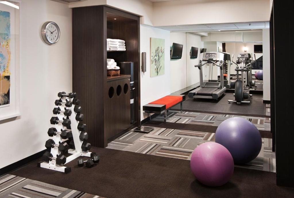 Fitnessruimte van The Prince George Hotel, Halifax met dumbbells, oefenballen, loopband, spiegel en trainingsbank.
