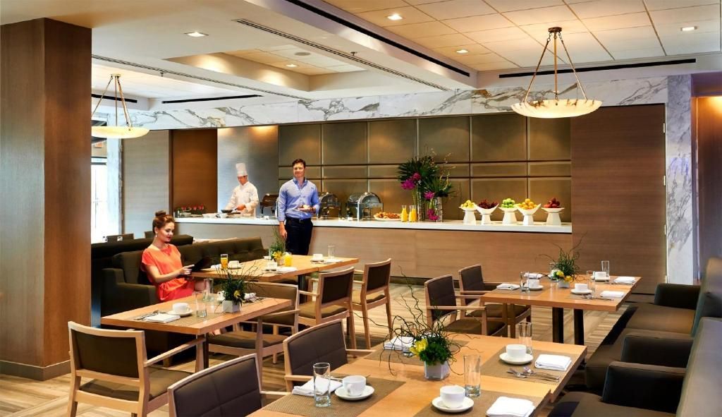 Moderne restaurantzaal van The Prince George Hotel, Halifax met gedekte tafels en een paar mensen bij de bar.