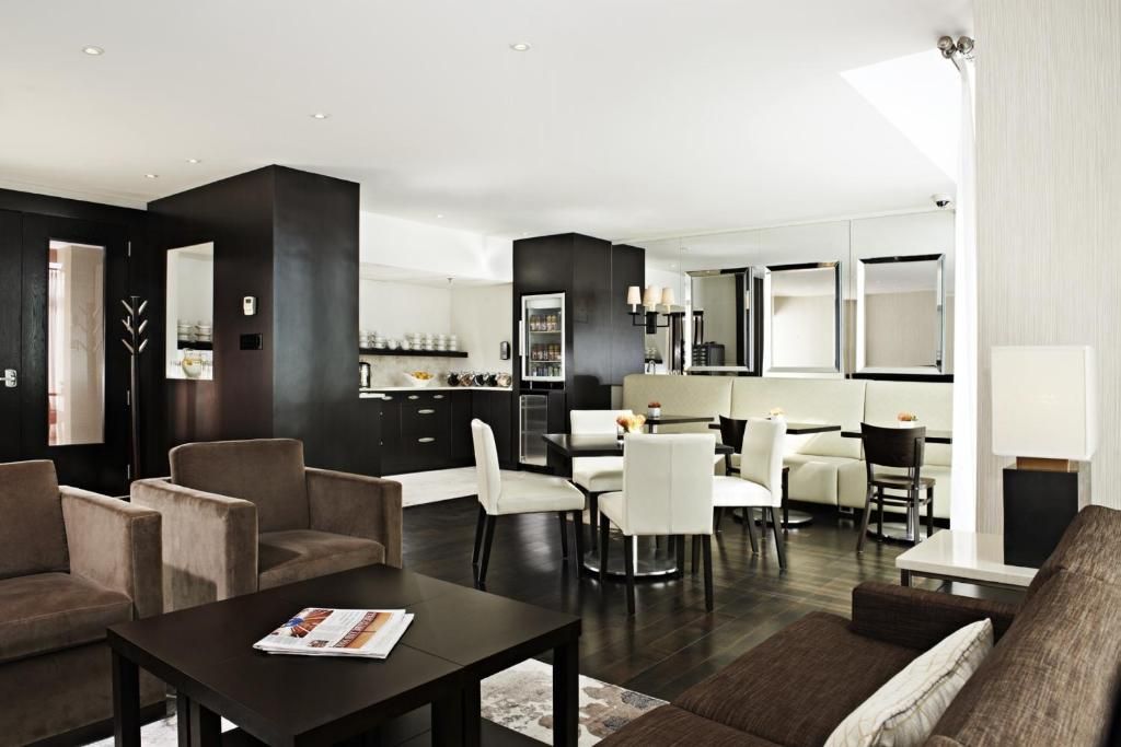 Moderne open lounge van The Prince George Hotel, Halifax met donker meubilair en witte stoelen, gezien vanaf een bank.