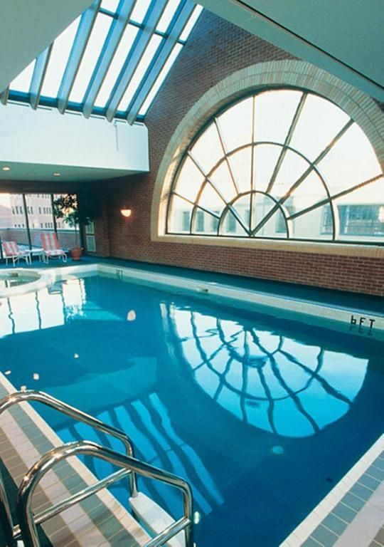 Binnenzwembad van The Prince George Hotel, Halifax met blauw water, boogvormige ramen en reflecties van het dakraam.