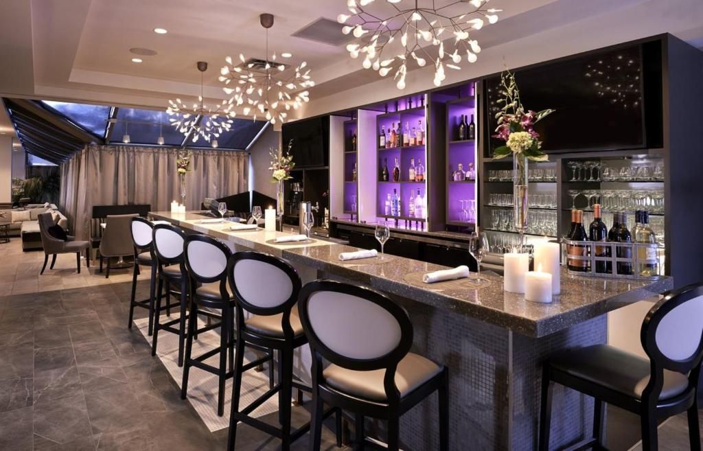 Elegante bar van The Prince George Hotel, Halifax met paars verlichte planken, een spiegelende toonbank en hoge barkrukken in een moderne lounge.