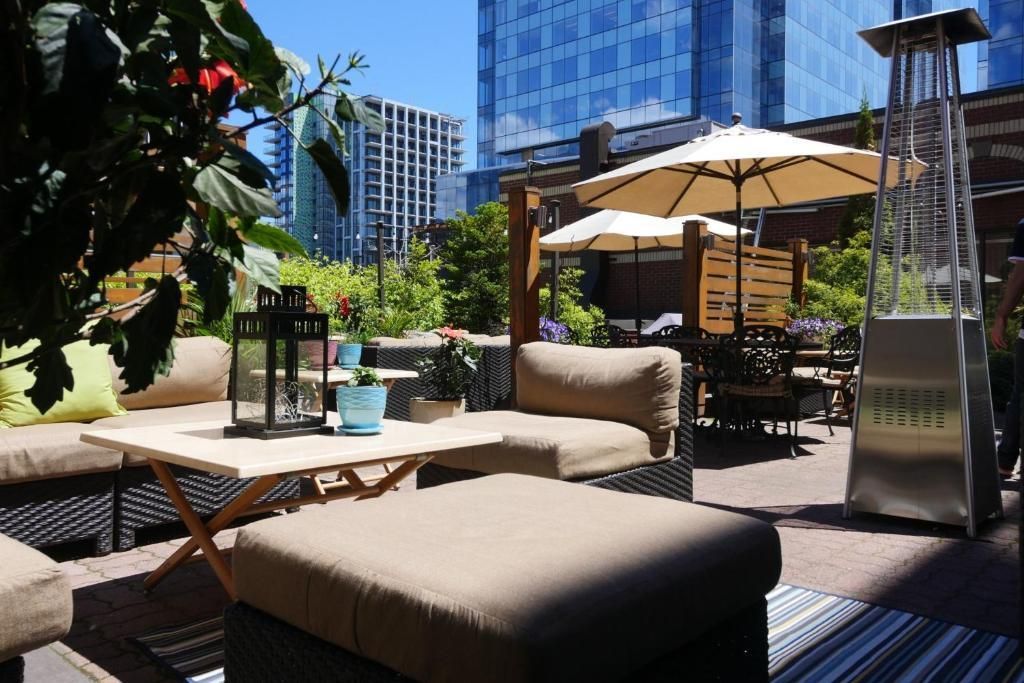 Buitenlounge op het dakterras van The Prince George Hotel, Halifax met beige zitmeubels, parasols en stadsgezicht op de achtergrond.