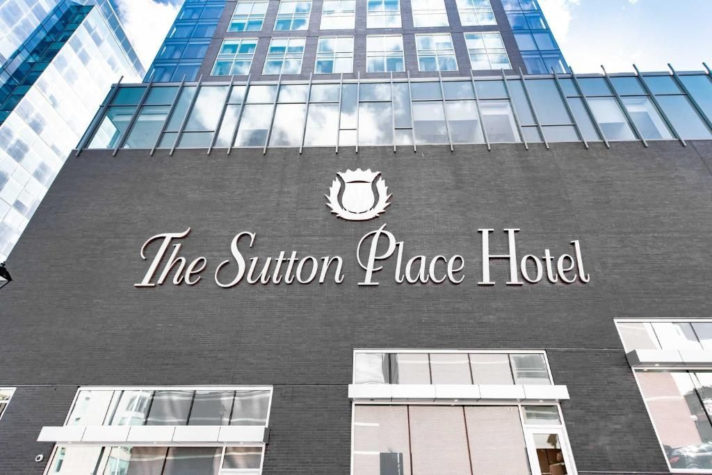 Het uithangbord van het Sutton Place Hotel op een grijs gebouw met glazen ramen erboven.