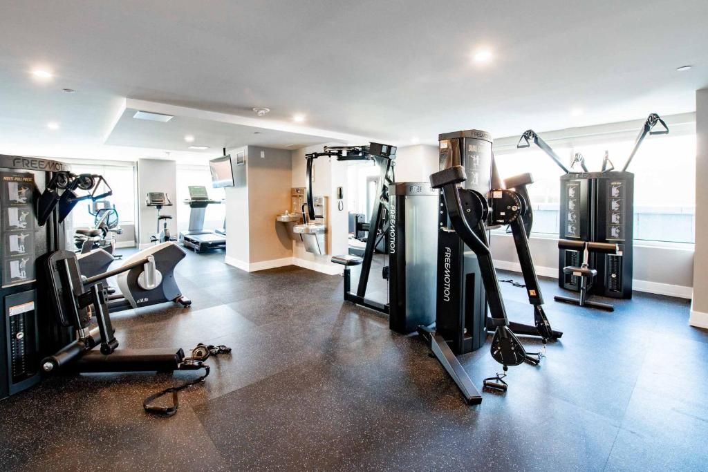 Modern fitnesscentrum met fitnessapparaten en lichte ramen.