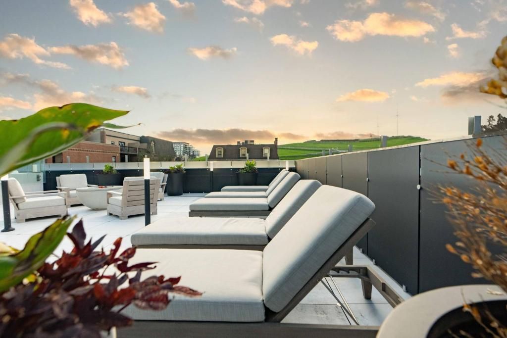 Dakterras met witte loungestoelen en plantenbakken onder een zonsondergang.