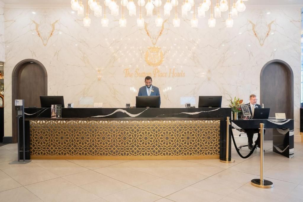 Hotelreceptiebalie met twee personeelsleden en een front met luipaardprint in een lichte lobby.