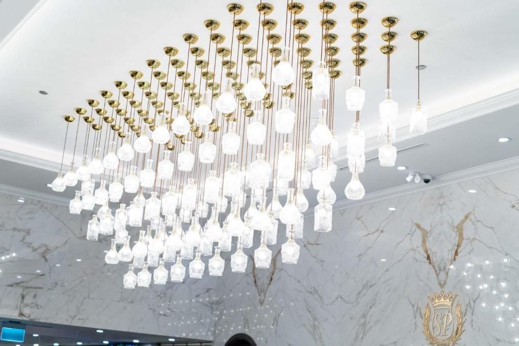 Moderne goud-witte kroonluchterinstallatie met hangende kristallen pendels aan een marmeren plafond.