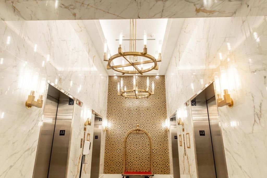 Luxueuze marmeren liftlobby met gouden accenten en een kroonluchter.