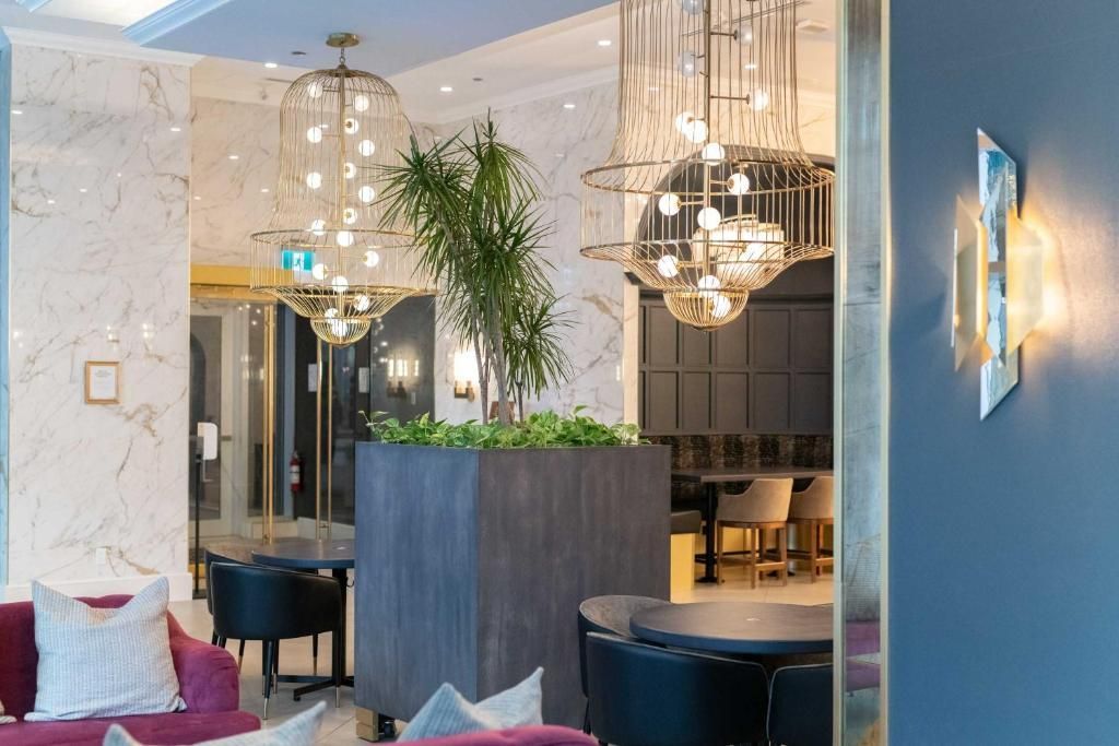 Elegant restaurantinterieur met blauwe muren, hangende kroonluchters en een grote potplant.