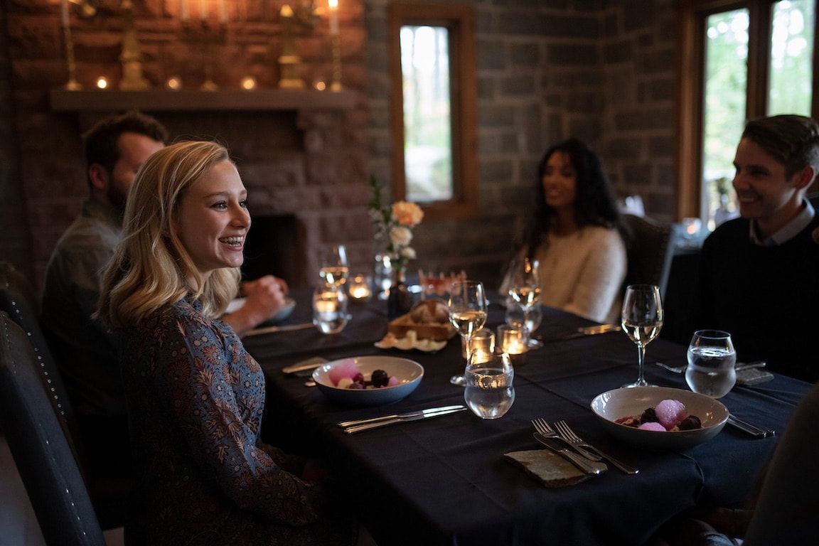 Vrienden die samen dineren in een sfeervol verlicht restaurant, glimlachend rond een tafel bij kaarslicht met wijn en hapjes.