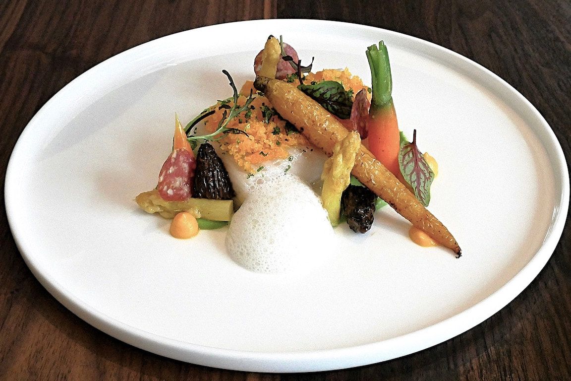 Een prachtig opgemaakt gerecht met groenten en saus op een wit bord.
