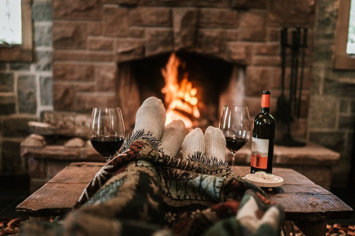 Gezellige scène bij de open haard met wijn, glazen en een met een deken bedekte tafel in een rustieke hut.
