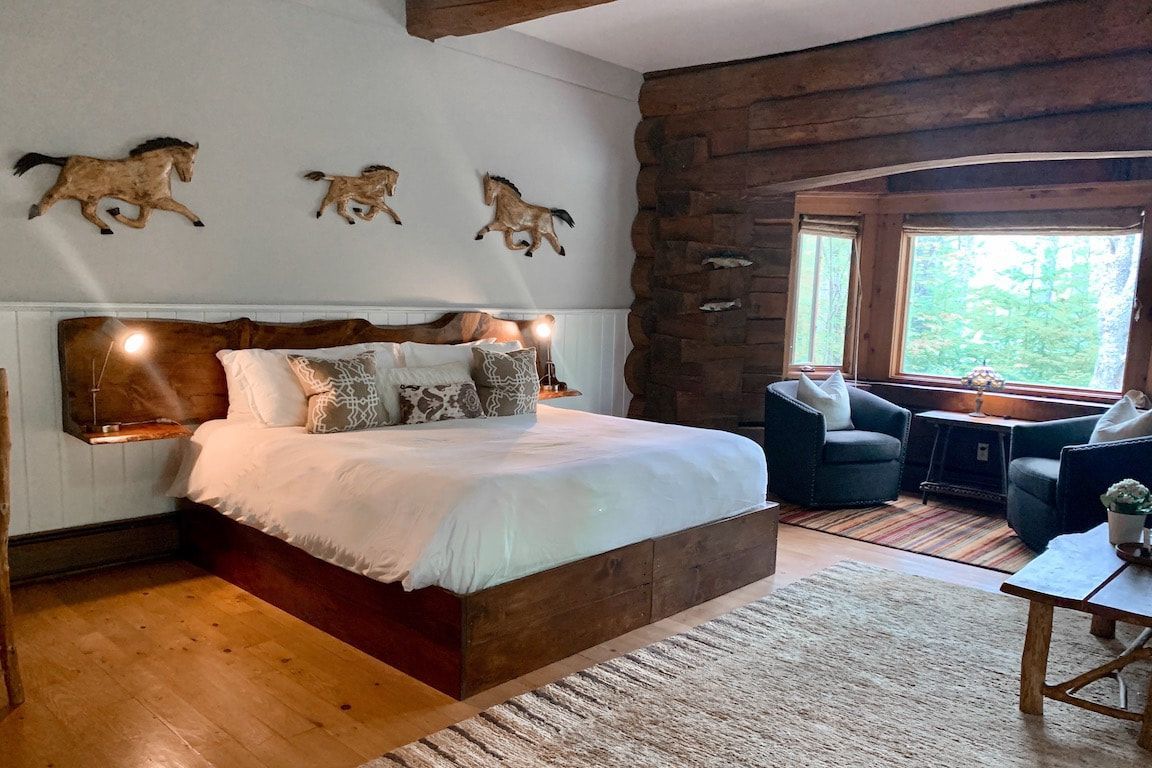 Gezellige slaapkamer met een bed, een bakstenen accentmuur, dierenkunst aan de muur en een vensterbank bij een groot raam.