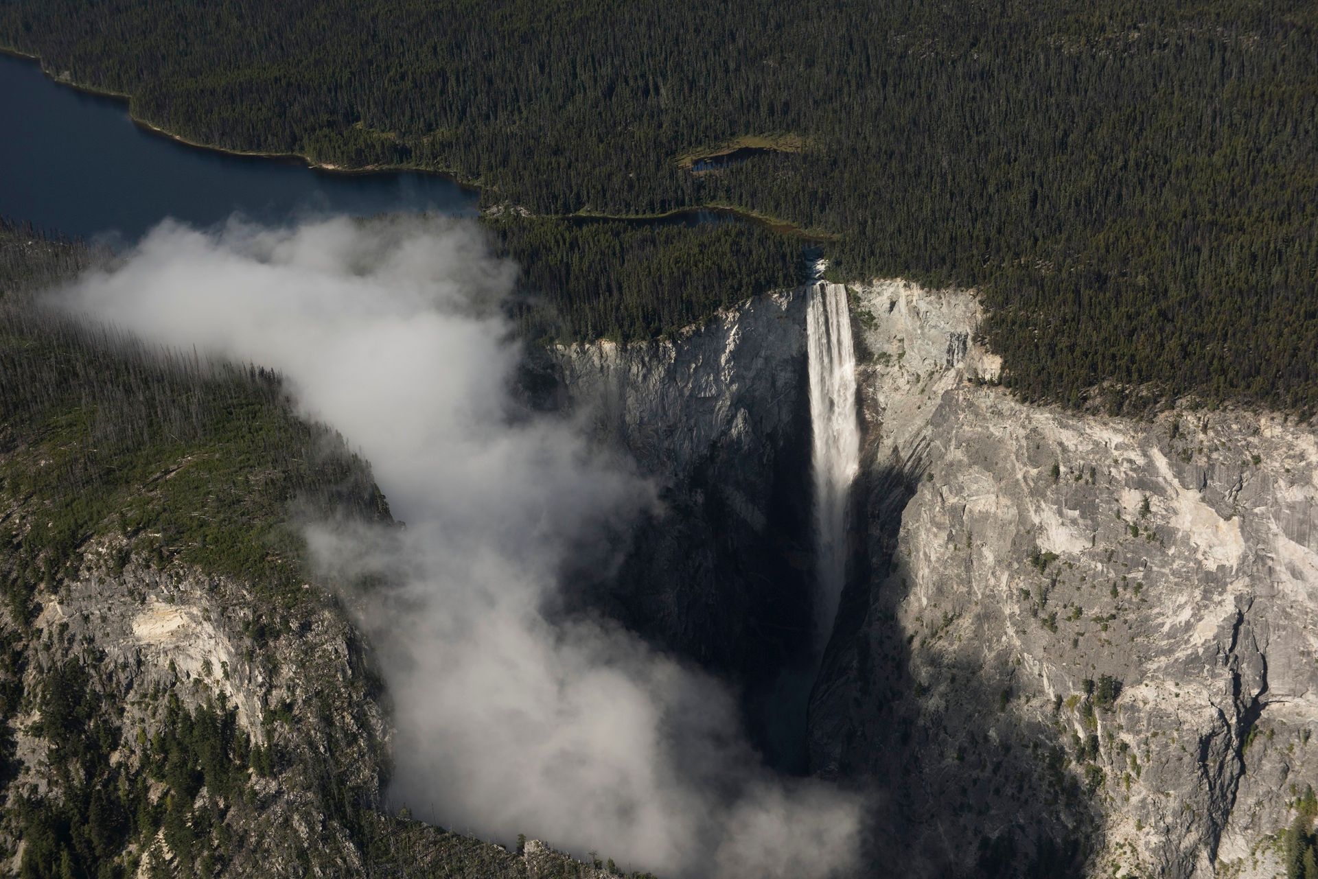 Luchtfoto van de Hunlen Falls die neerstort in een diepe, beboste kloof, met mist die in de buurt opstijgt.