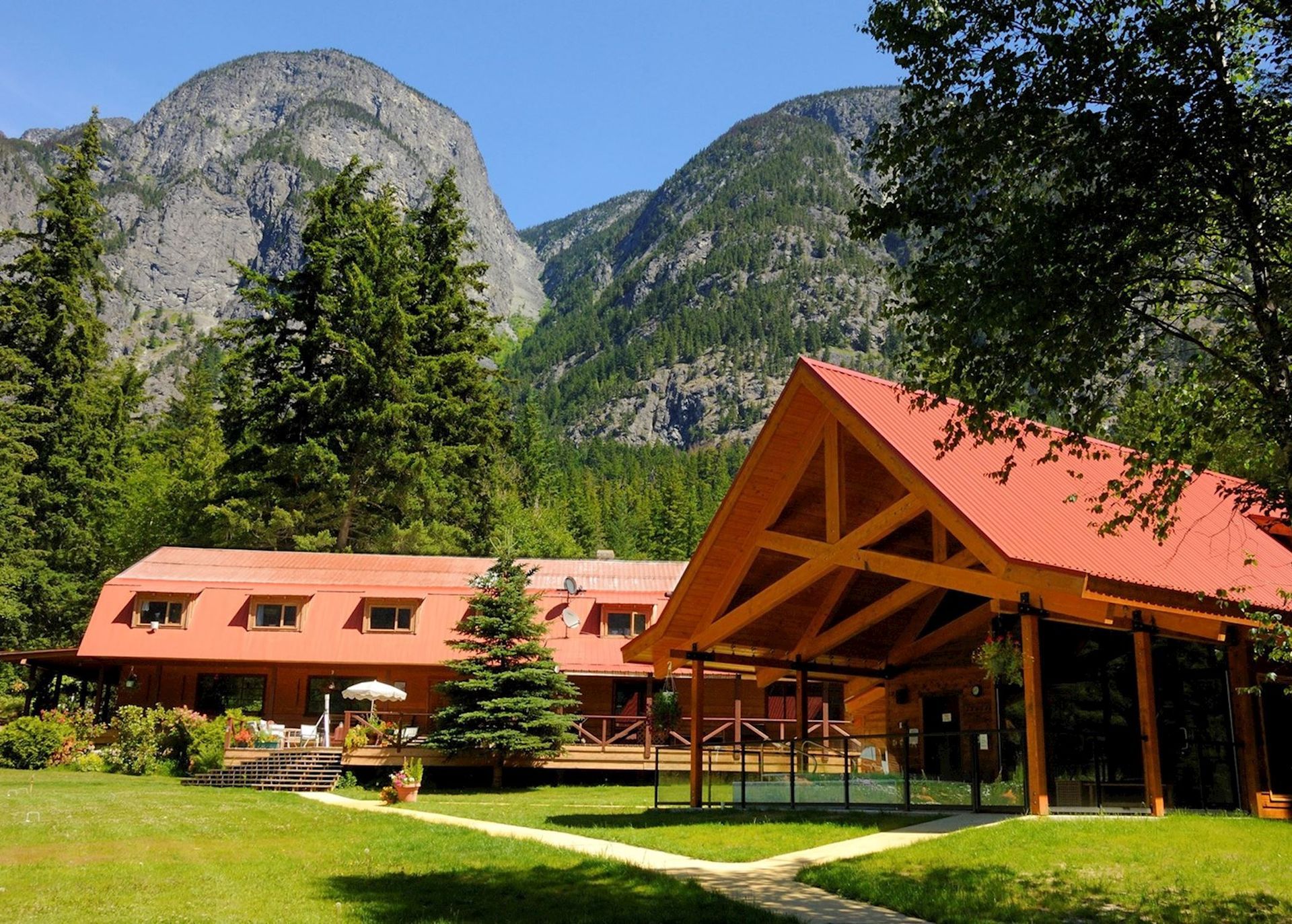 Het hoofdgebouw van Tweedsmuir Park Lodge en de wellness in een groene vallei onder rotsachtige bergtoppen.