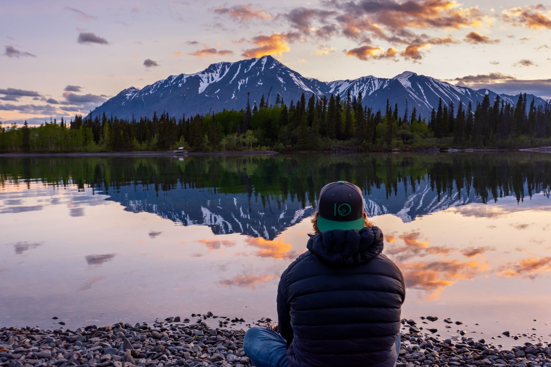 Kathleen Lake, Kluane National Park © Sheena Greenlaw Man zit aan het meer Kathleen Lake, Kluane National Park, Yukon, en kijkt naar de weerspiegeling van de bergen bij zonsondergang.
