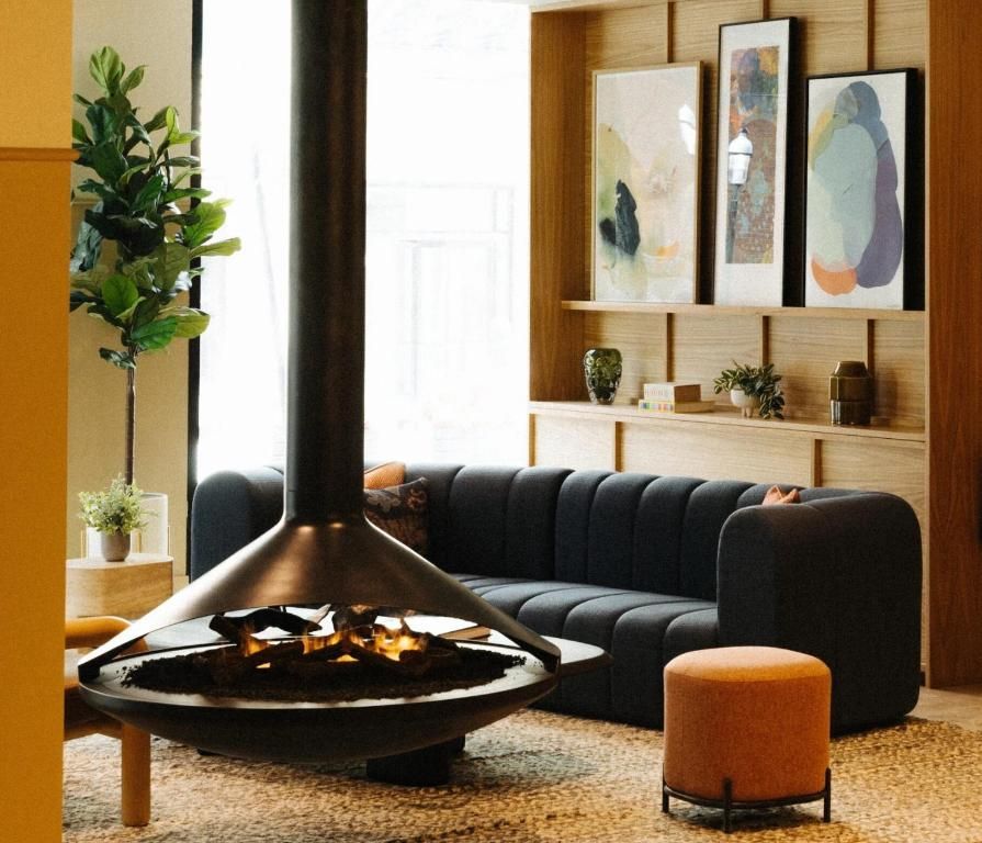 Moderne woonkamer met een hangende open haard, zwarte bank, potplant en abstracte muurdecoratie.