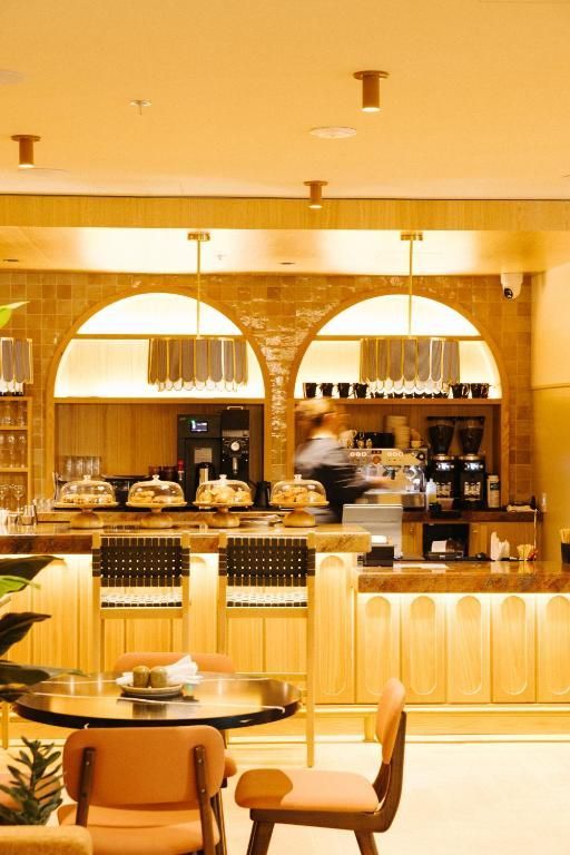 Een bar met warme tinten, gewelfde spiegels, flessen en barkrukken in een stijlvolle lounge.