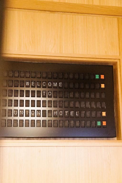 Braillebord met reliëftekst in een houten frame, met gekleurde knoppen aan de rechterkant.
