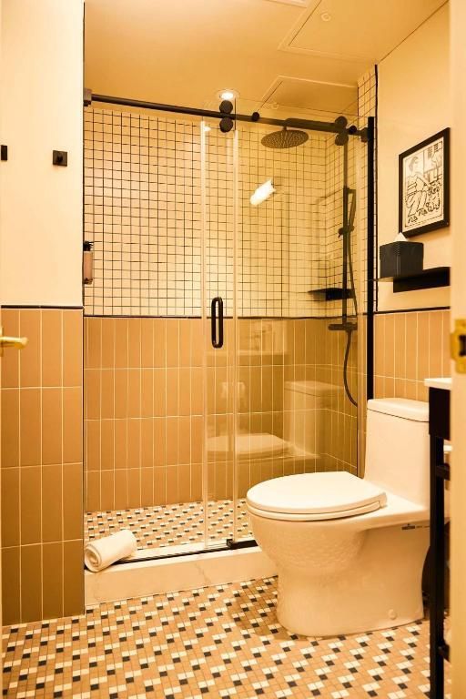 Toegankelijke badkamer met douche, toilet en beige betegelde wanden en vloer.
