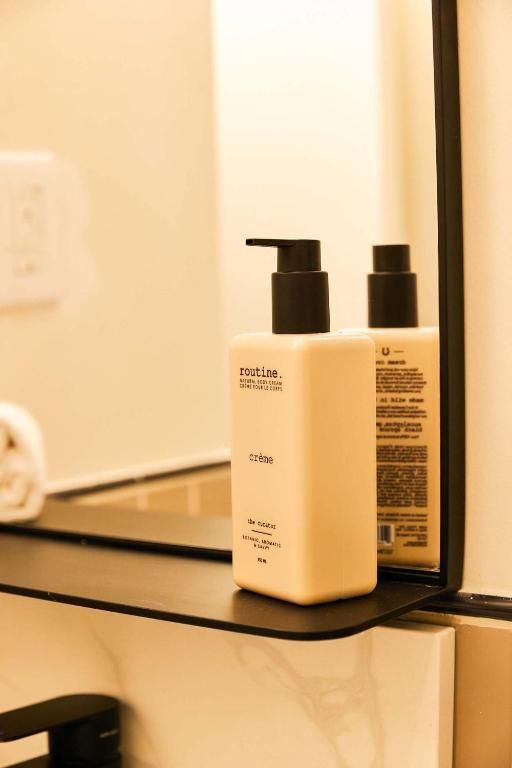 Twee flesjes lotion op een plankje in de badkamer naast de spiegel.