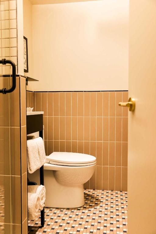 Kleine badkamer met een toilet, beige tegelwanden en een vloer met een patroon.