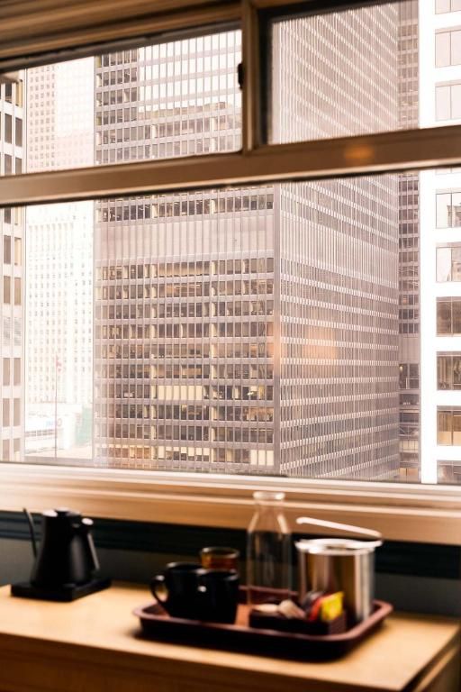 Hotelraam met uitzicht op de wolkenkrabbers van de stad, met een dienblad met koffie en thee op tafel.