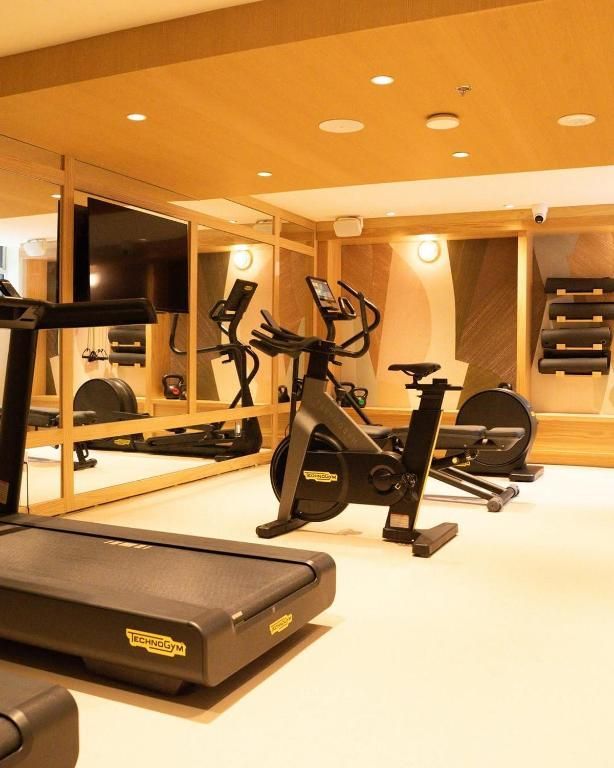 Moderne fitnessruimte met hometrainer, loopband, spiegels en sfeervolle verlichting.