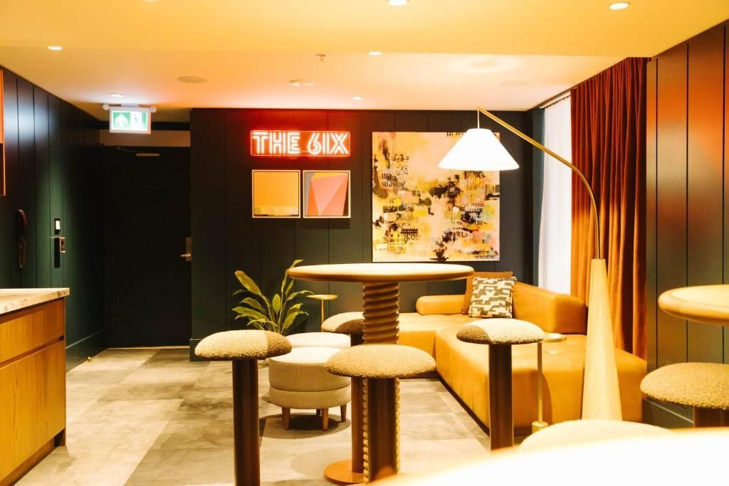 Moderne loungehoek met beige zitmeubelen, houten tafels, warme verlichting en een