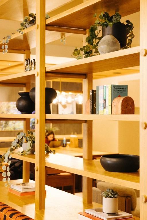 Houten planken met boeken, planten en decoratieve schalen in een warm, modern interieur.