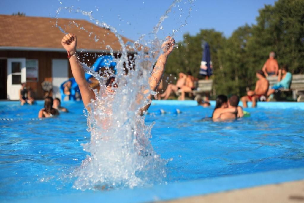 Mensen spetteren in een felblauw buitenzwembad op een zonnige dag.