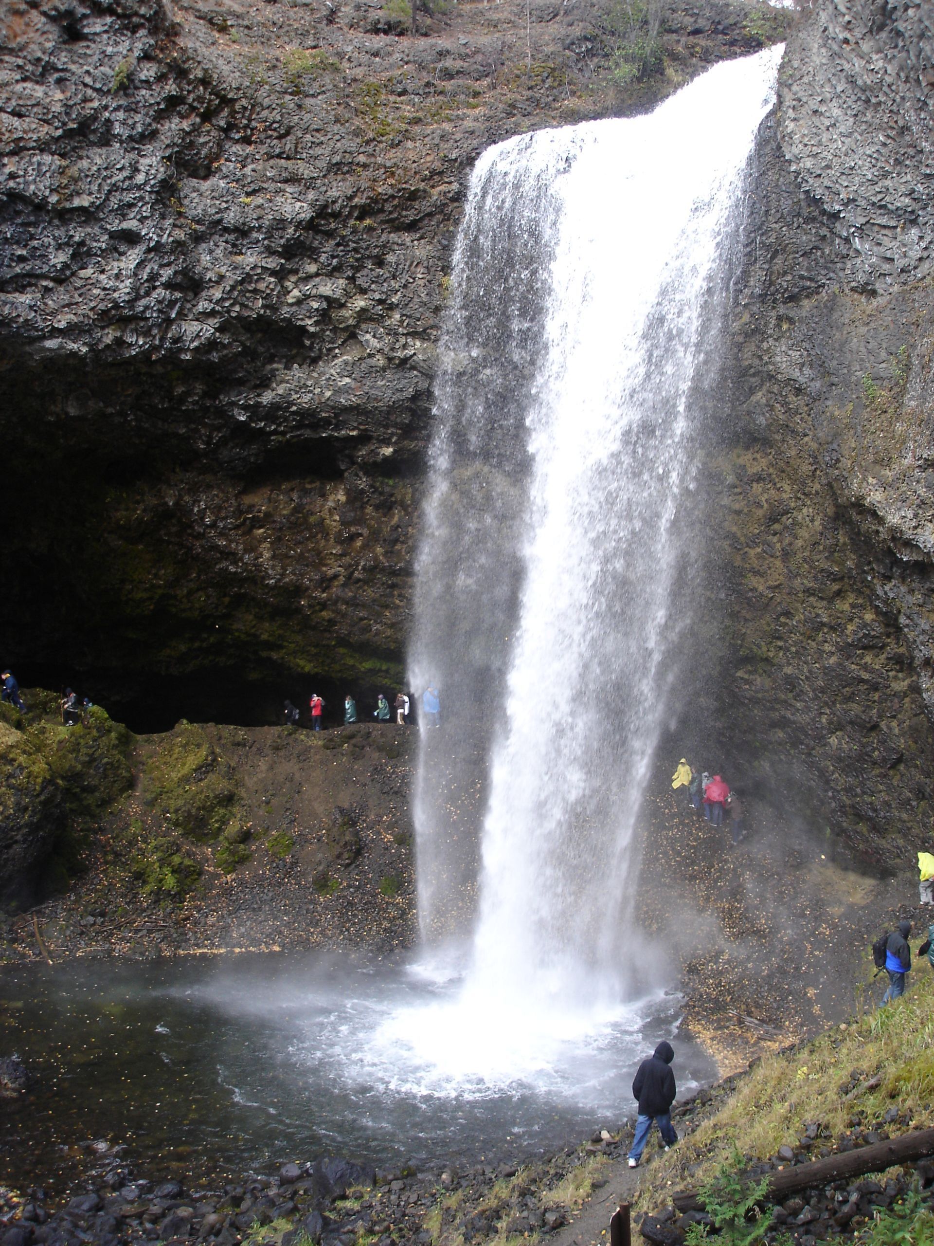 De Moul Falls in Well Grey Provincial Park stort neer in een poel, met mensen die aan de voet ervan staan ​​in een rotsachtige kloof.