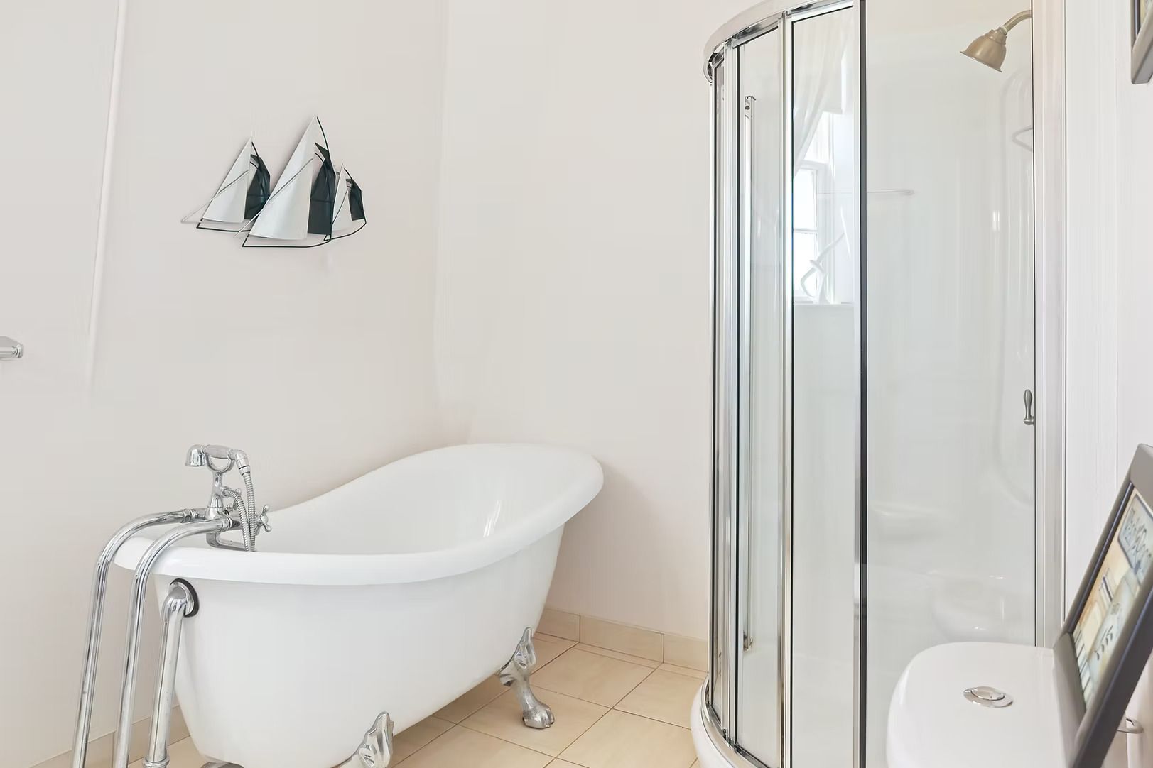 Lichte, witte badkamer met vrijstaand bad, douchecabine en grote spiegel boven de wastafel.