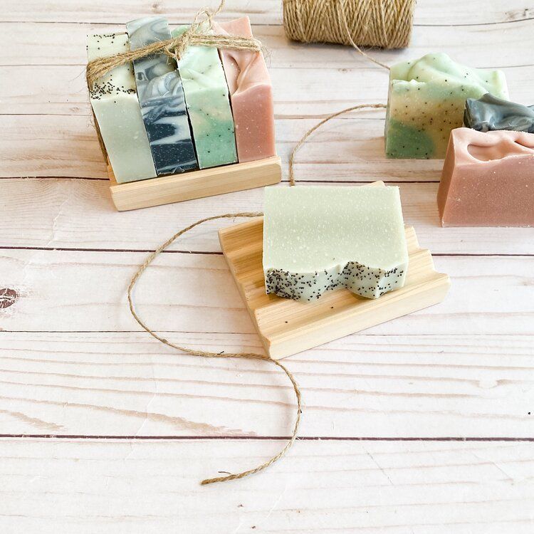 Pastelkleurige handgemaakte zeepjes op een witte houten tafel met touw en een klosje koord.