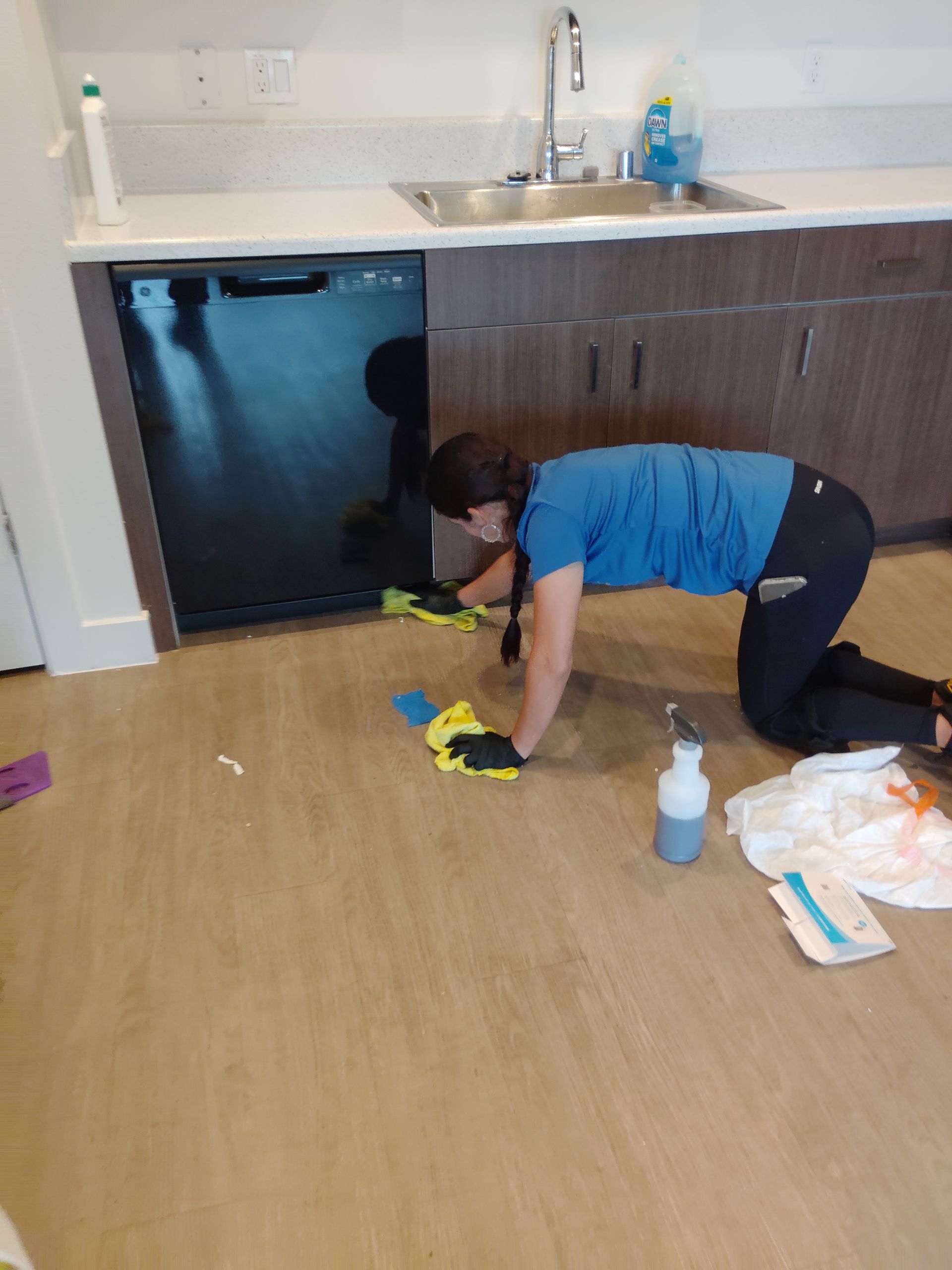 Worker operating a floor scrubber in a bright, modern lobby with tall glass windows