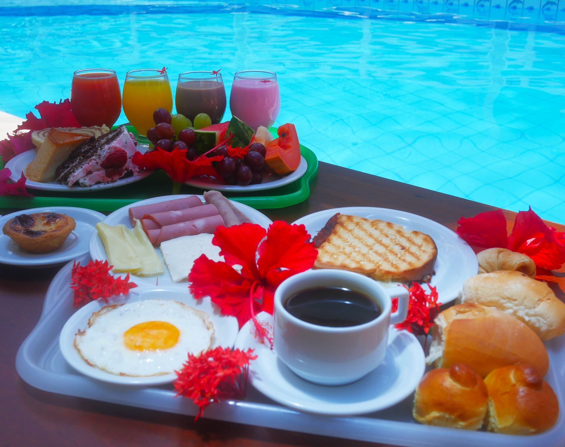 Uma bandeja de comida e bebidas ao lado de uma piscina