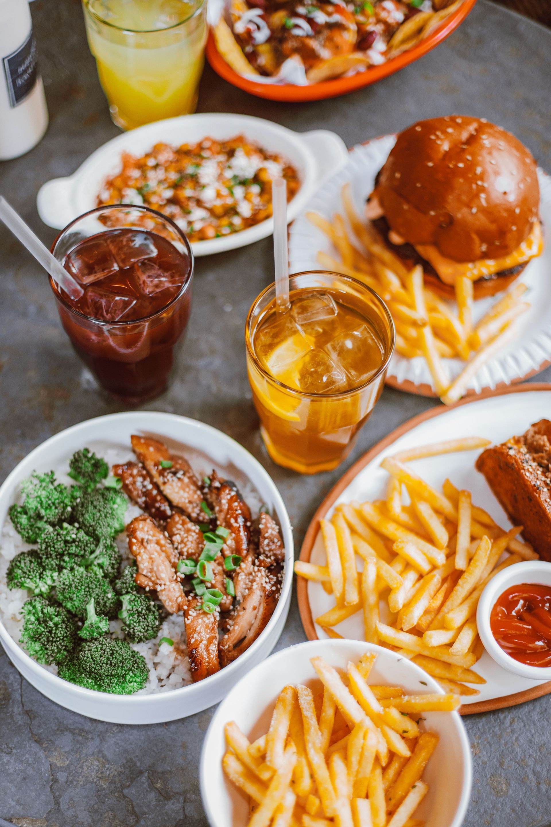 Assorted fast food spread on a table with fries, burgers, sandwiches, salads, and drinks