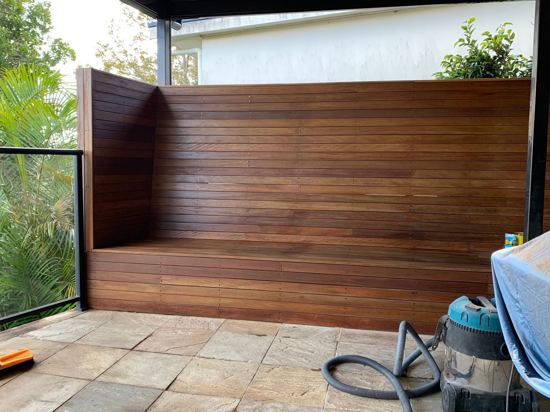 Wooden bench built into a privacy wall on a patio. Brown wood with visible grain.