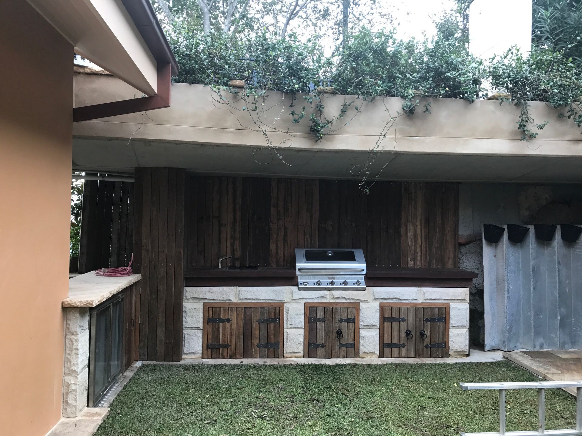 Outdoor kitchen with grill, wood paneling, and stone accents.