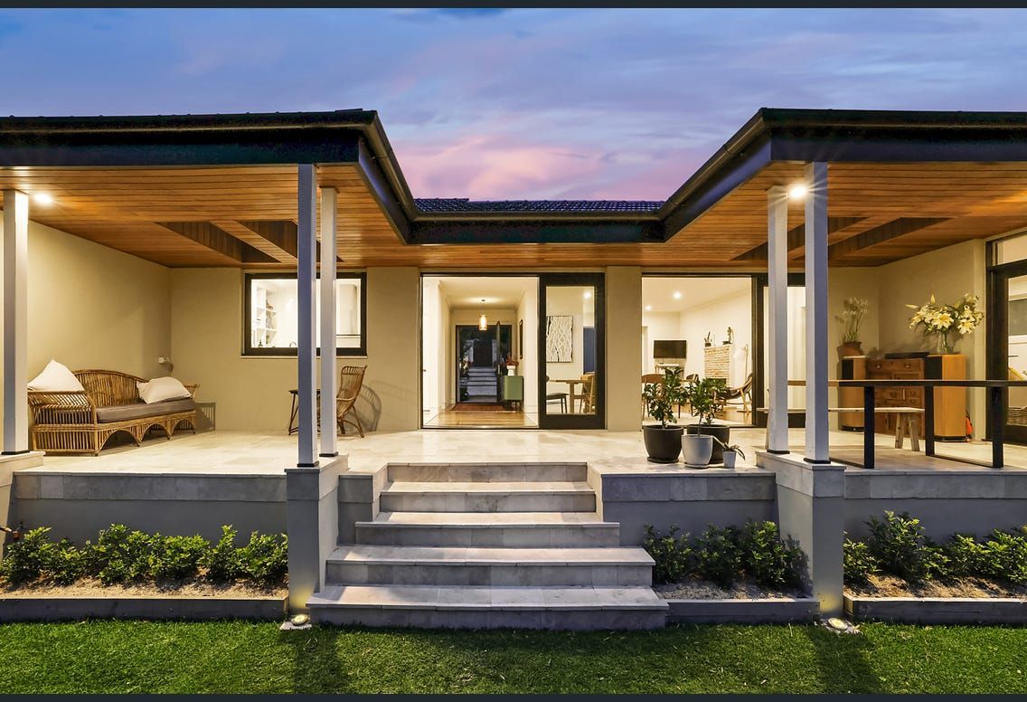 Exterior of a modern home with covered porch, steps, and landscaping; twilight sky.