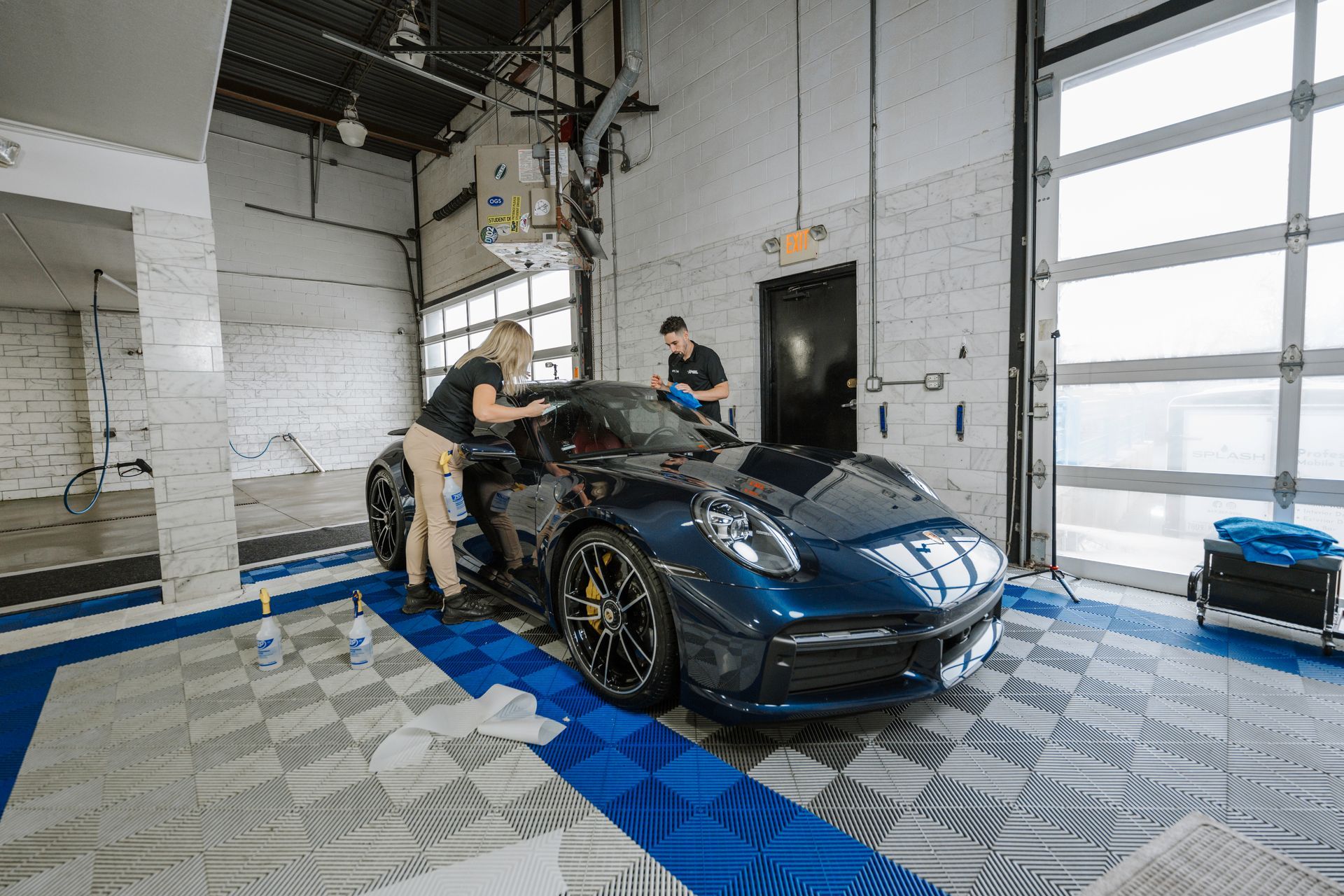 A man and a woman are working on a car in a garage.