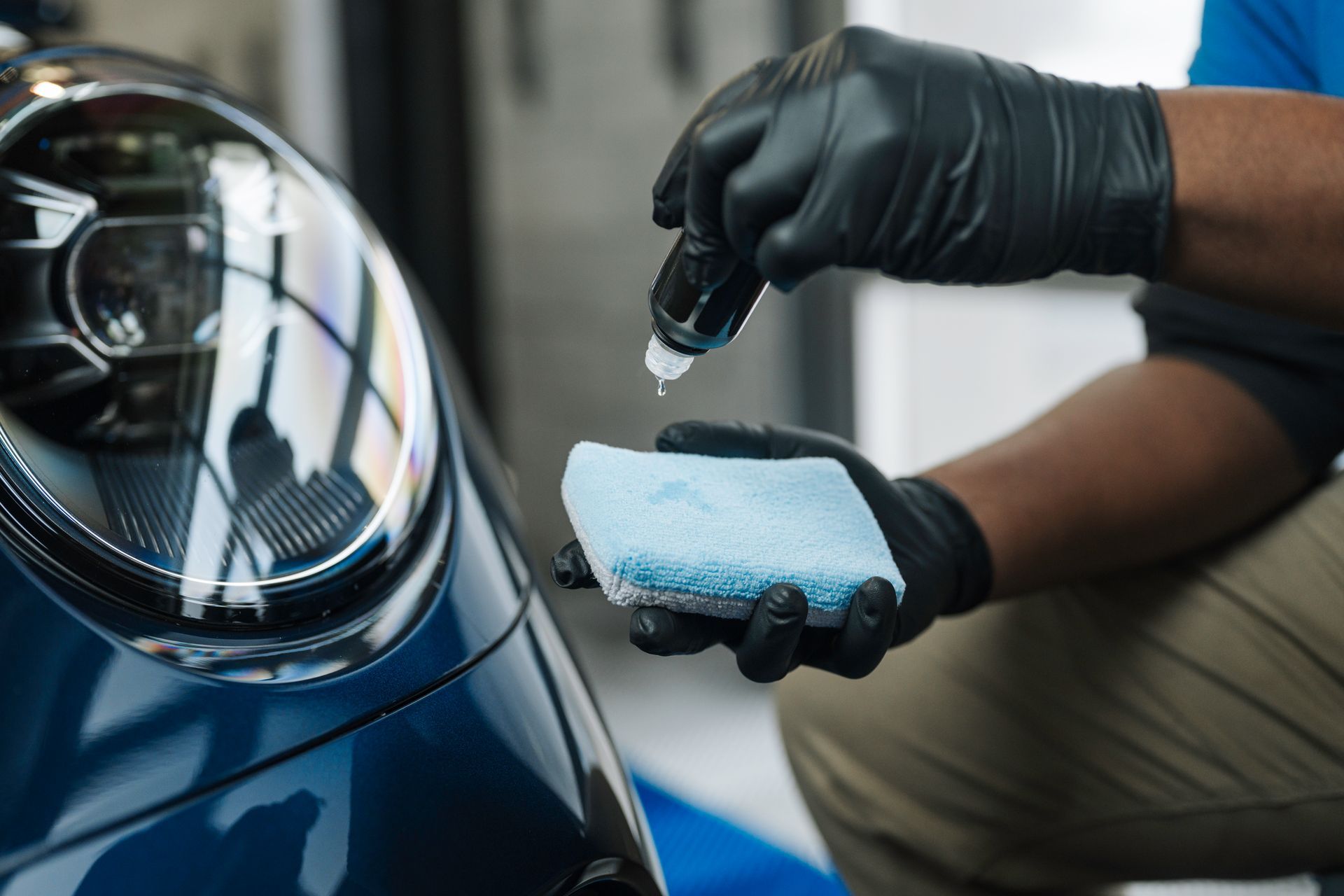 A man is applying a coating to a car headlight.