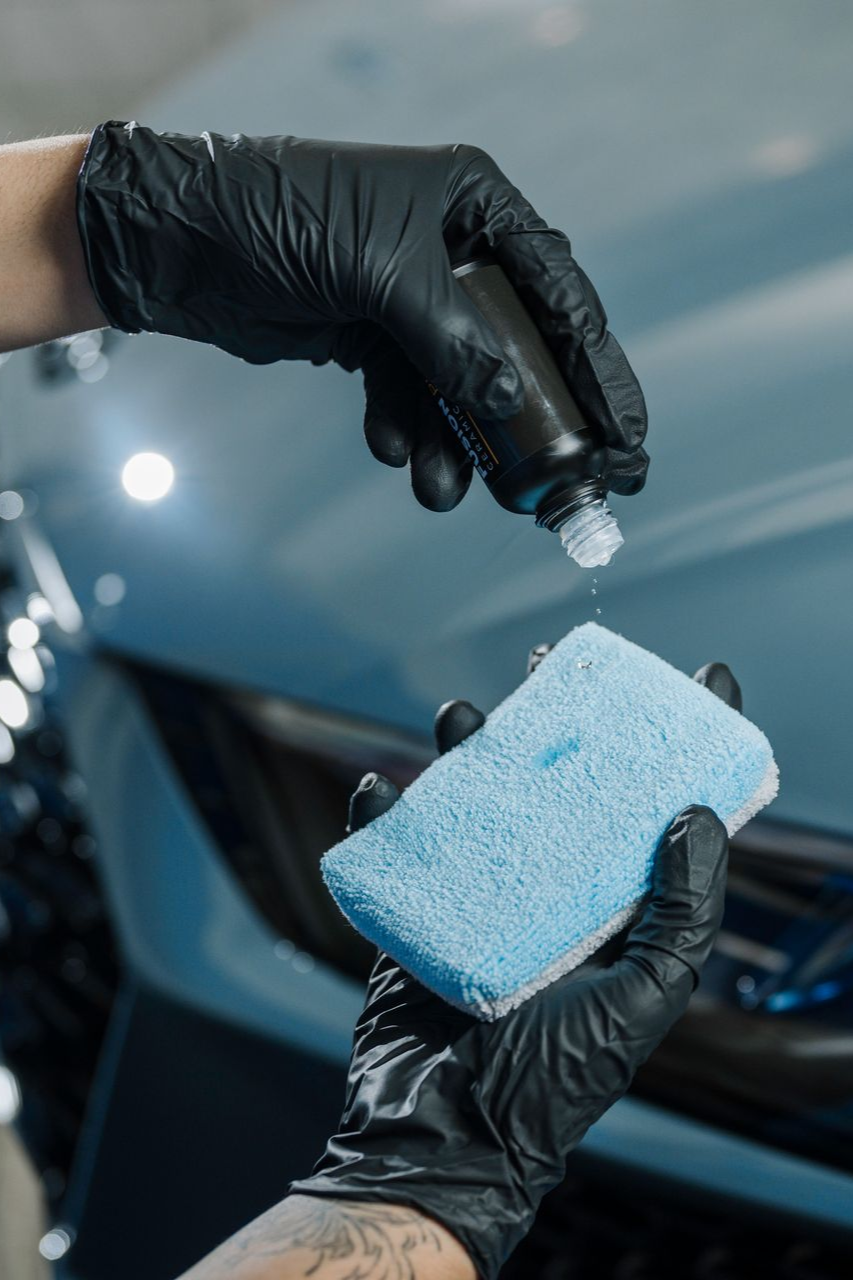 A person is cleaning a car with a sponge and a spray bottle.