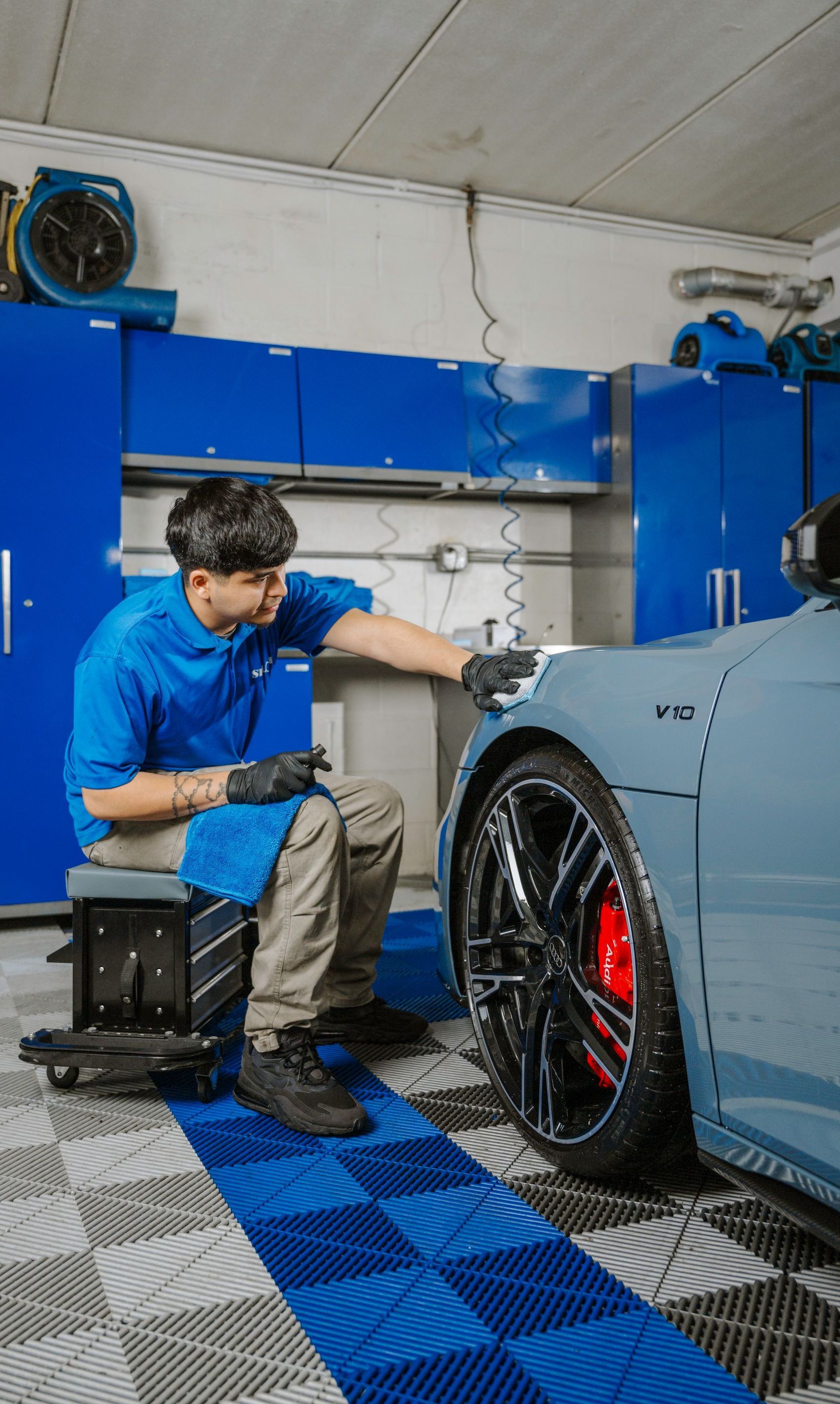 A man is cleaning a car in a garage.