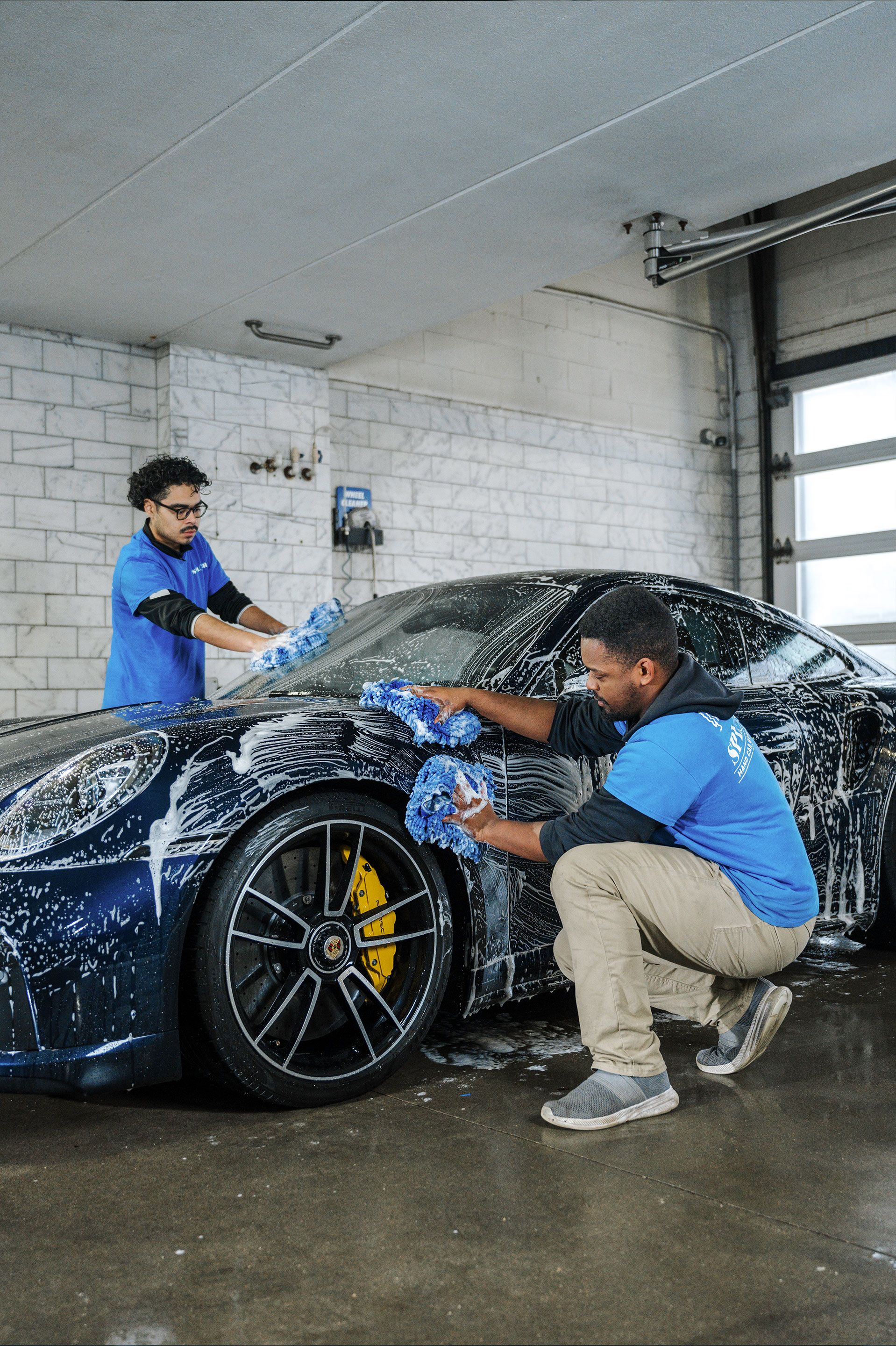 Two men are washing a car in a car wash.
