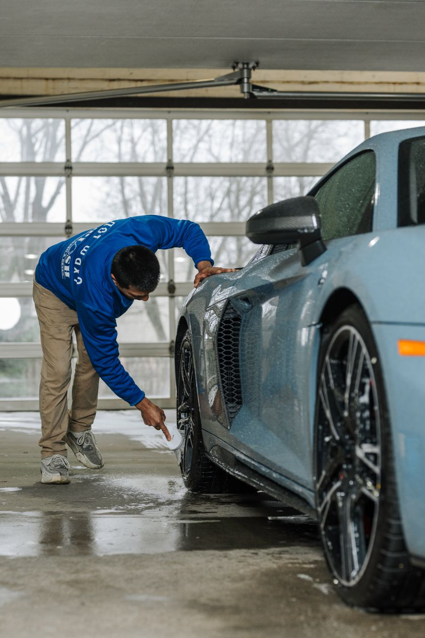 A man is washing a car in a garage.