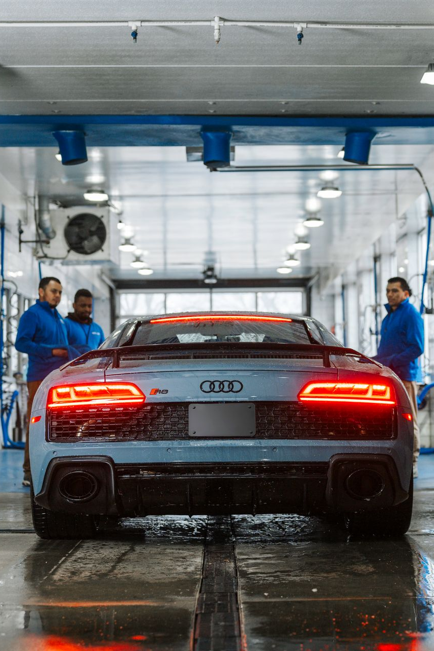 A man is standing next to a car in a garage.