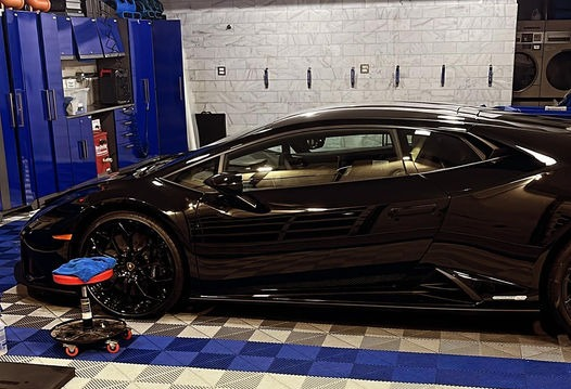 A black sports car is parked in a garage.